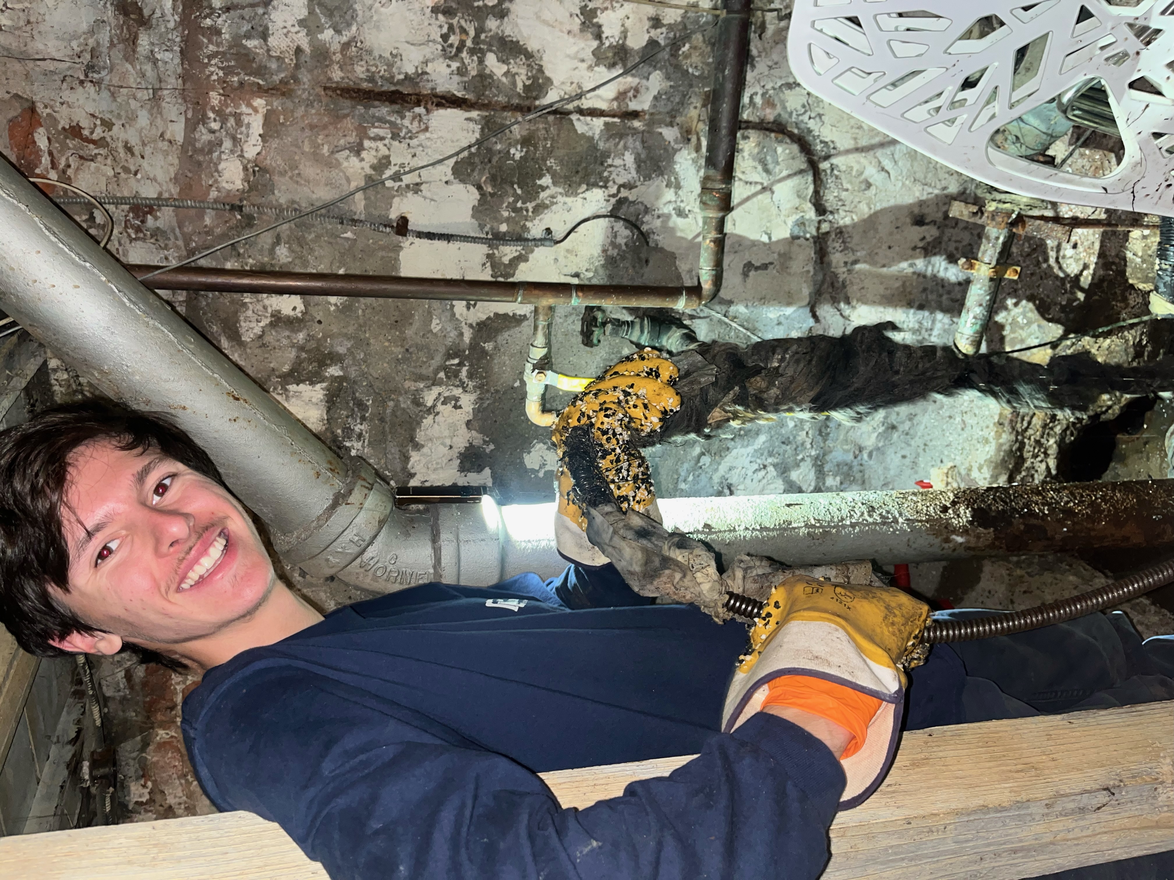 A plumber working on a clogged drain in a New York City basement.