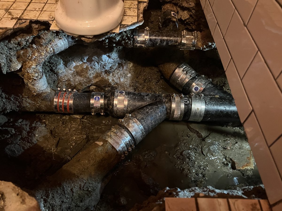 Replaced section of building drain under a bathroom floor, joined to the old cast iron with no-hub couplings.