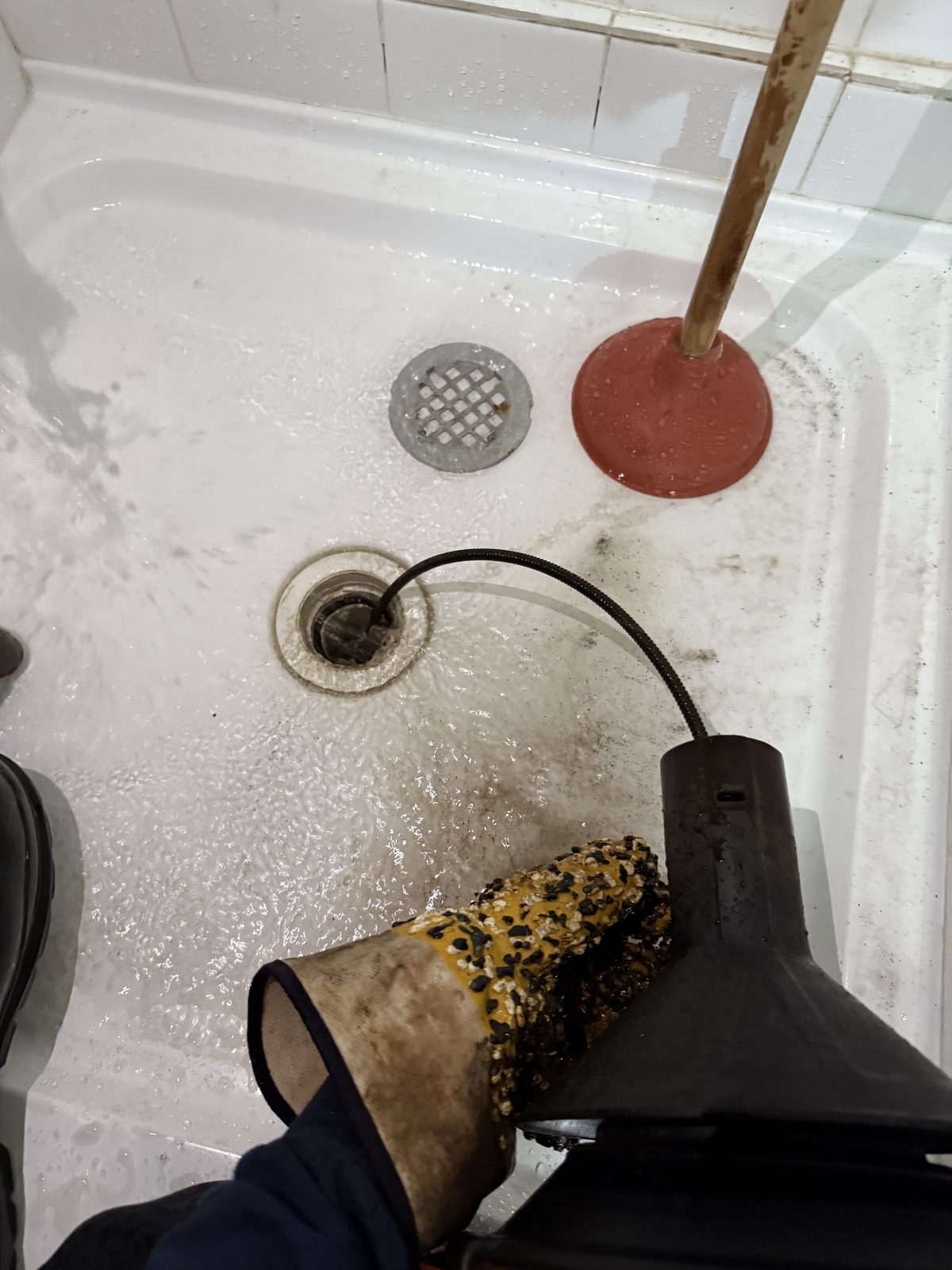 Clearing a blocked shower drain with a drain machine.